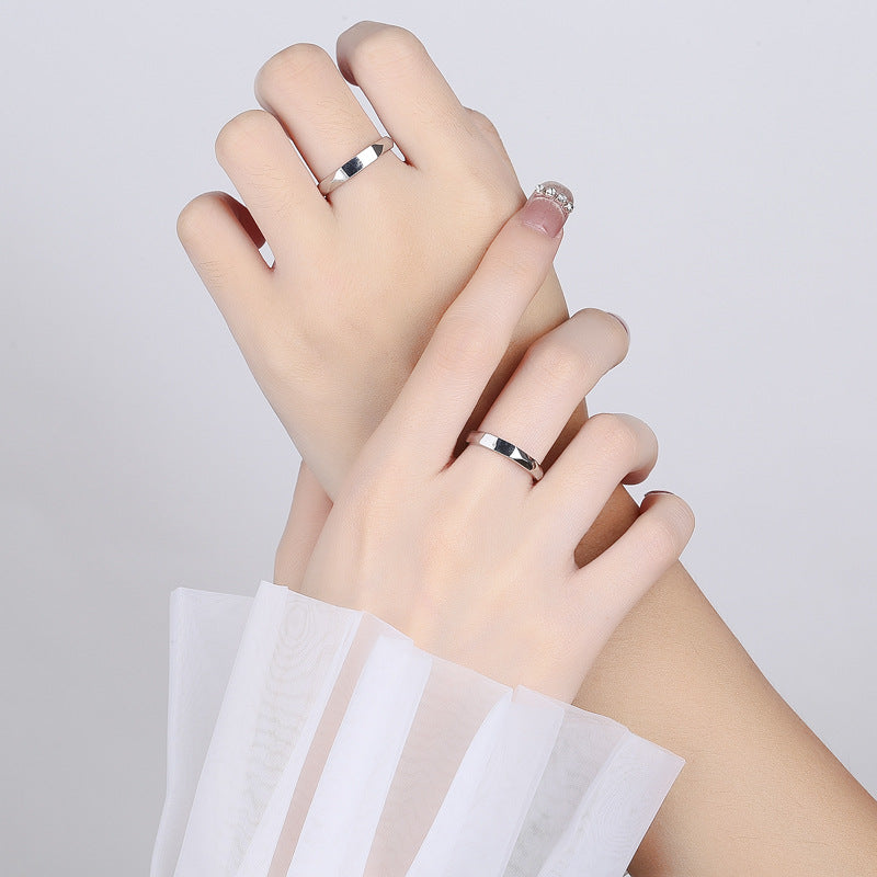 Two hands wearing matching Jingqian S925 Sterling Silver Light Reflection Rings are intertwined against a white background. One hand has a sheer white fabric draped over the wrist, while the other wears a clear, beaded nail accent on the pinky finger. The light reflection from the rings adds an extra touch of elegance.