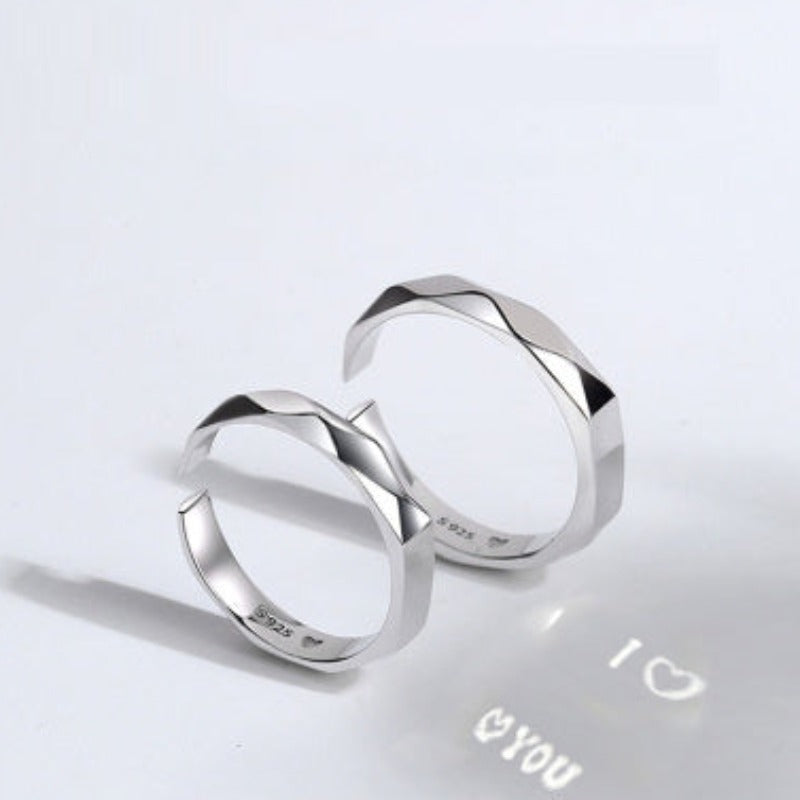 Two S925 Sterling Silver Light Reflection Rings by Jingqian with faceted surfaces are shown on a white background. The interior of the adjustable rings has inscriptions, and a projection below them displays "I ❤ YOU" with a heart symbol, capturing light reflections beautifully.