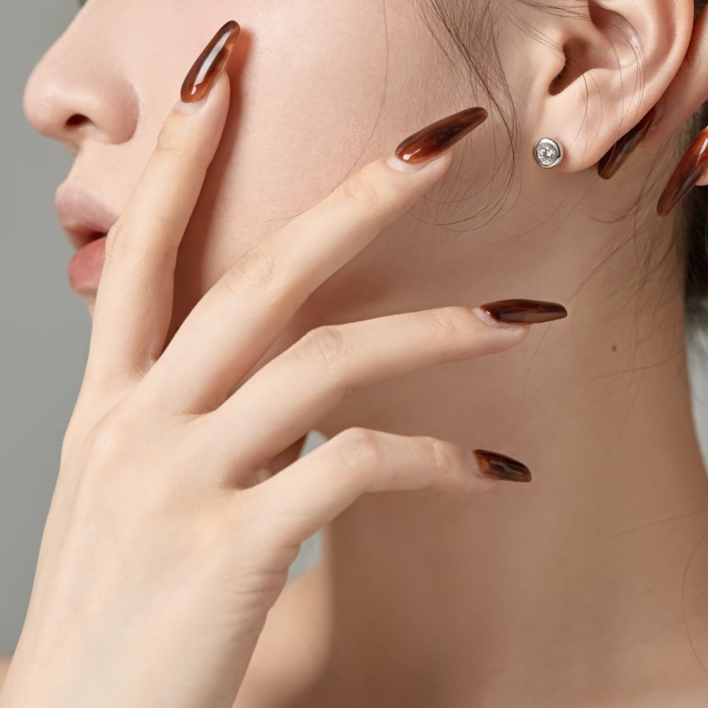 Close-up of a person wearing a diamond earring with a neutral background