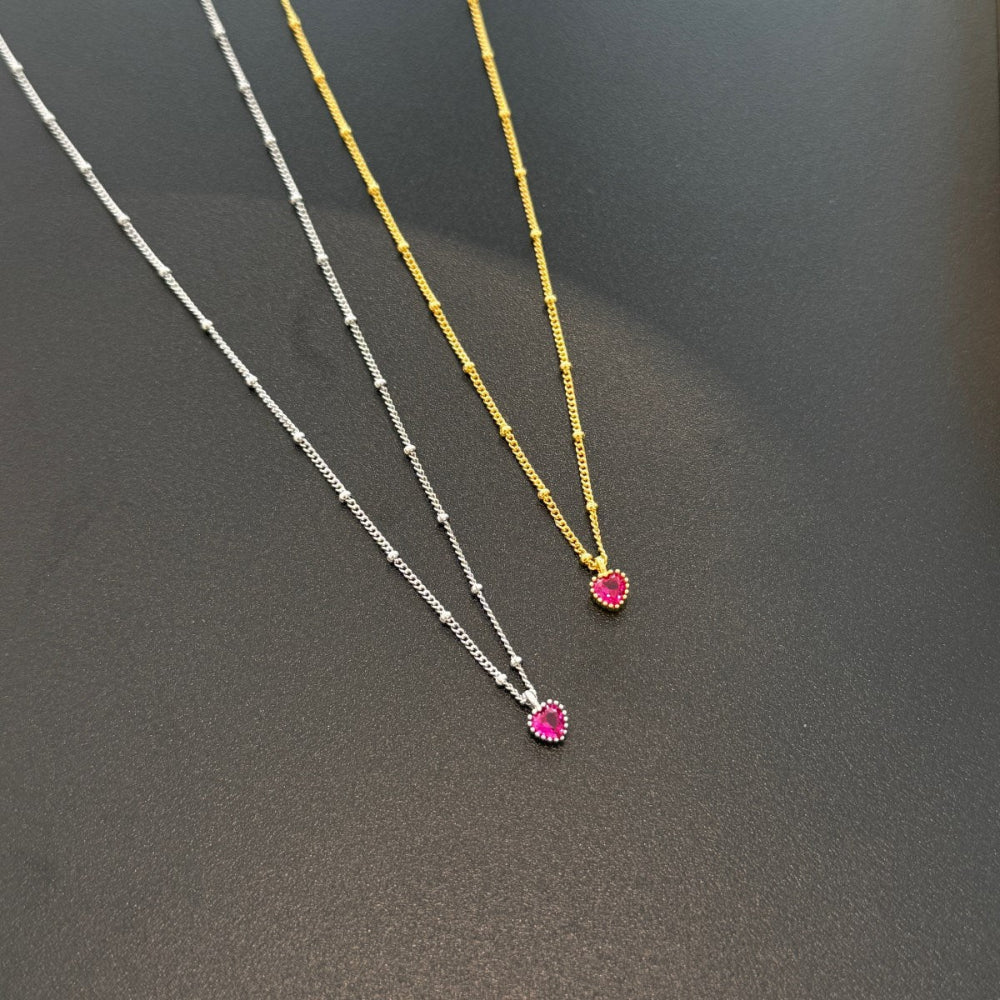 Two necklaces with heart-shaped pendants on a dark surface