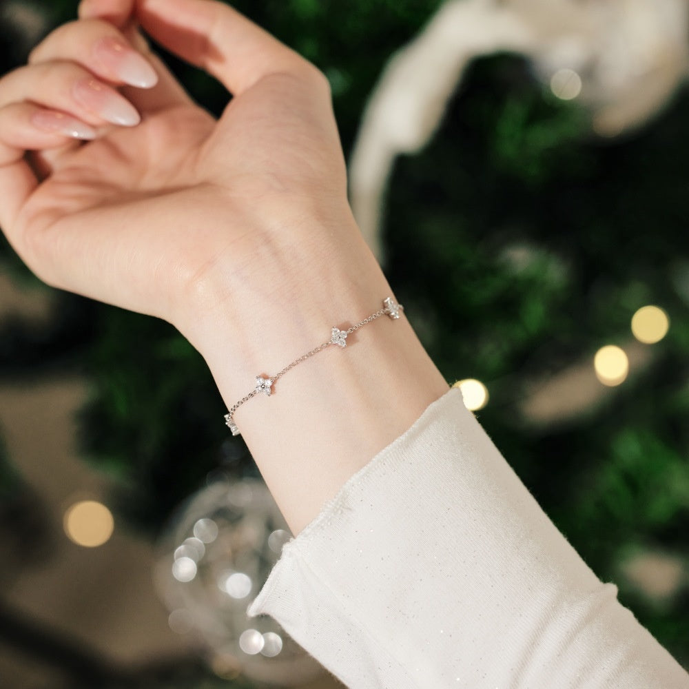 Hand wearing a delicate bracelet with a blurred festive background