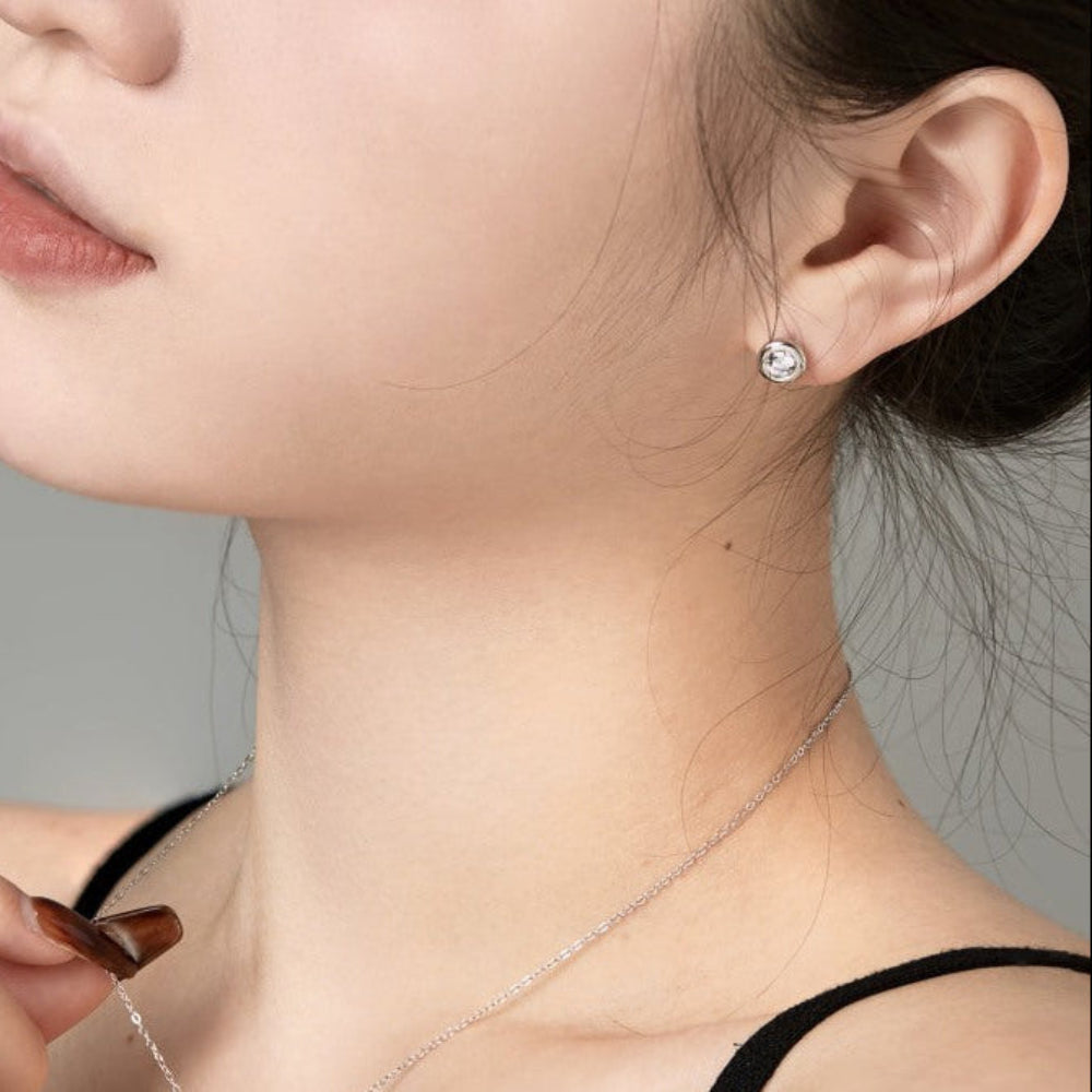 Woman wearing a necklace, earrings, and ring with a neutral background