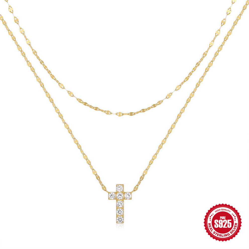 Gold necklace with a diamond cross pendant on a white background, featuring a '925 Sterling Silver' stamp.