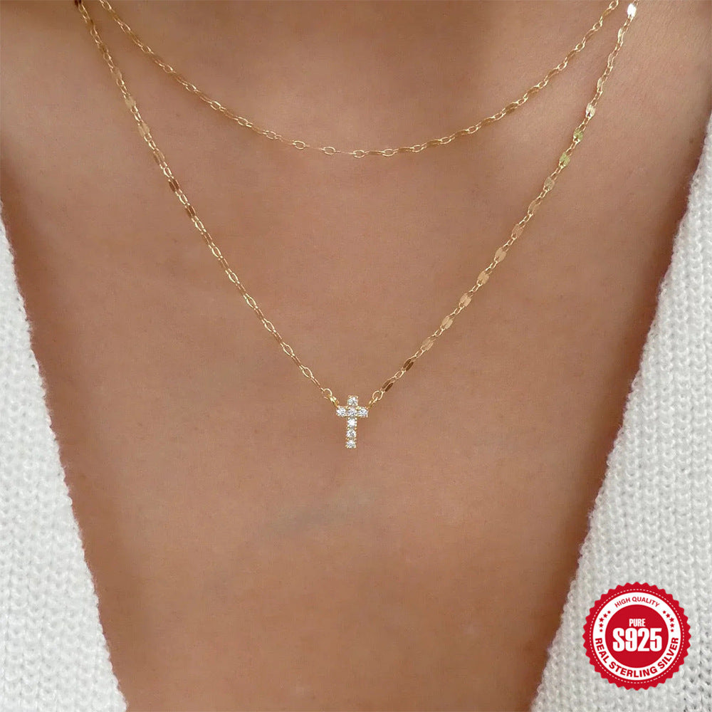 Gold necklace with a cross pendant on a person's neck, branded '925 Sterling Silver'.