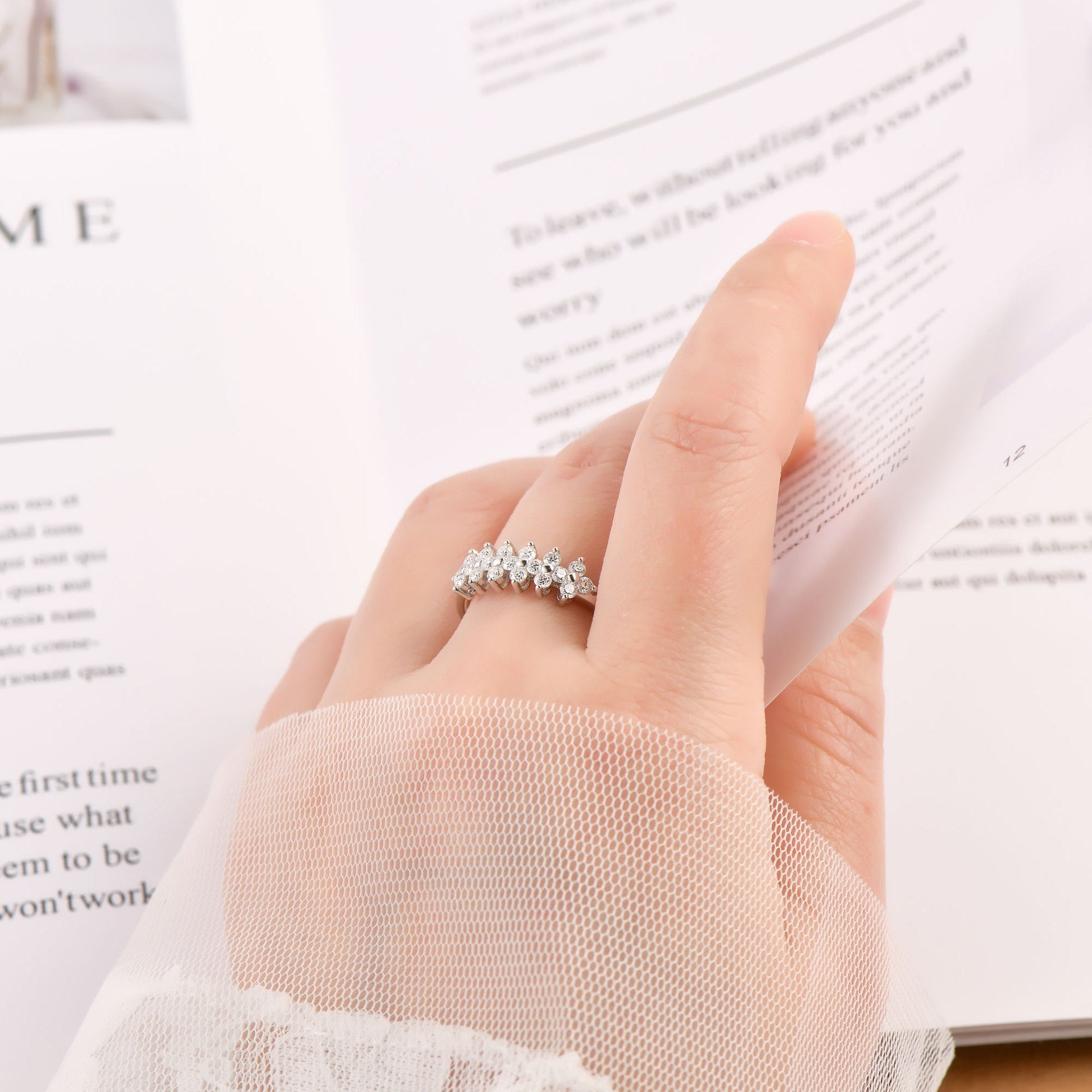 Hand wearing a silver ring on a blurred book background