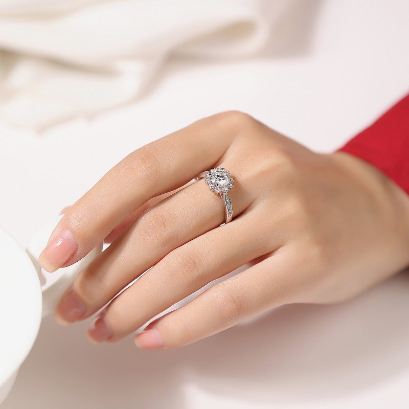 Hand wearing a silver ring with a diamond on a light background