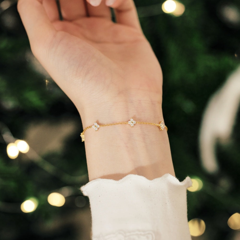 Gold bracelet on a wrist with a blurred festive background